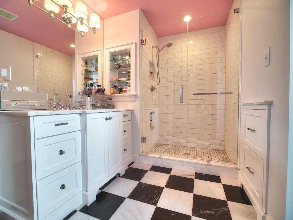 A bathroom with a pink ceiling and a black and white checkered floor.