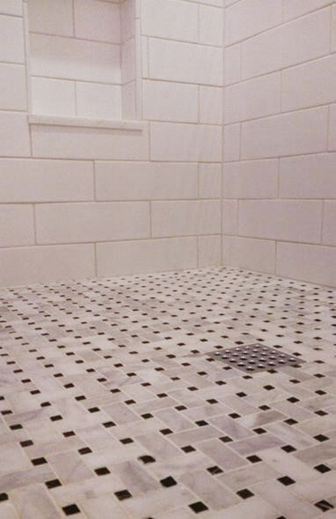 A shower with white tiles and a black and white checkered floor.