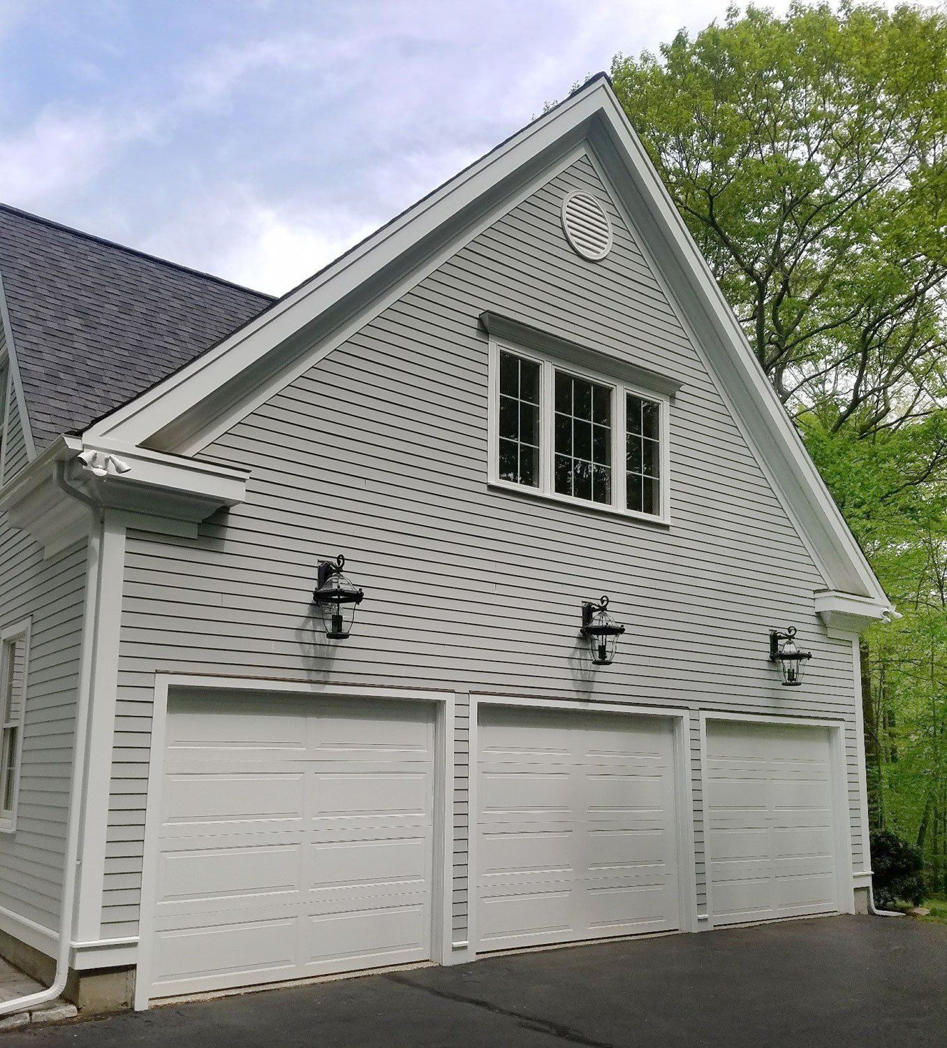 A white house with three garage doors and a roof