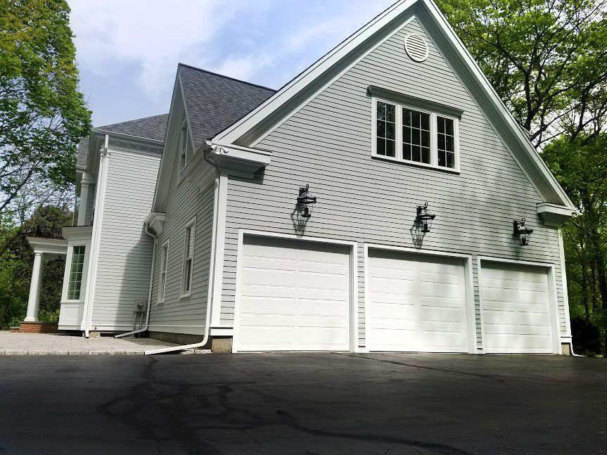 A large white house with three garage doors and a driveway.