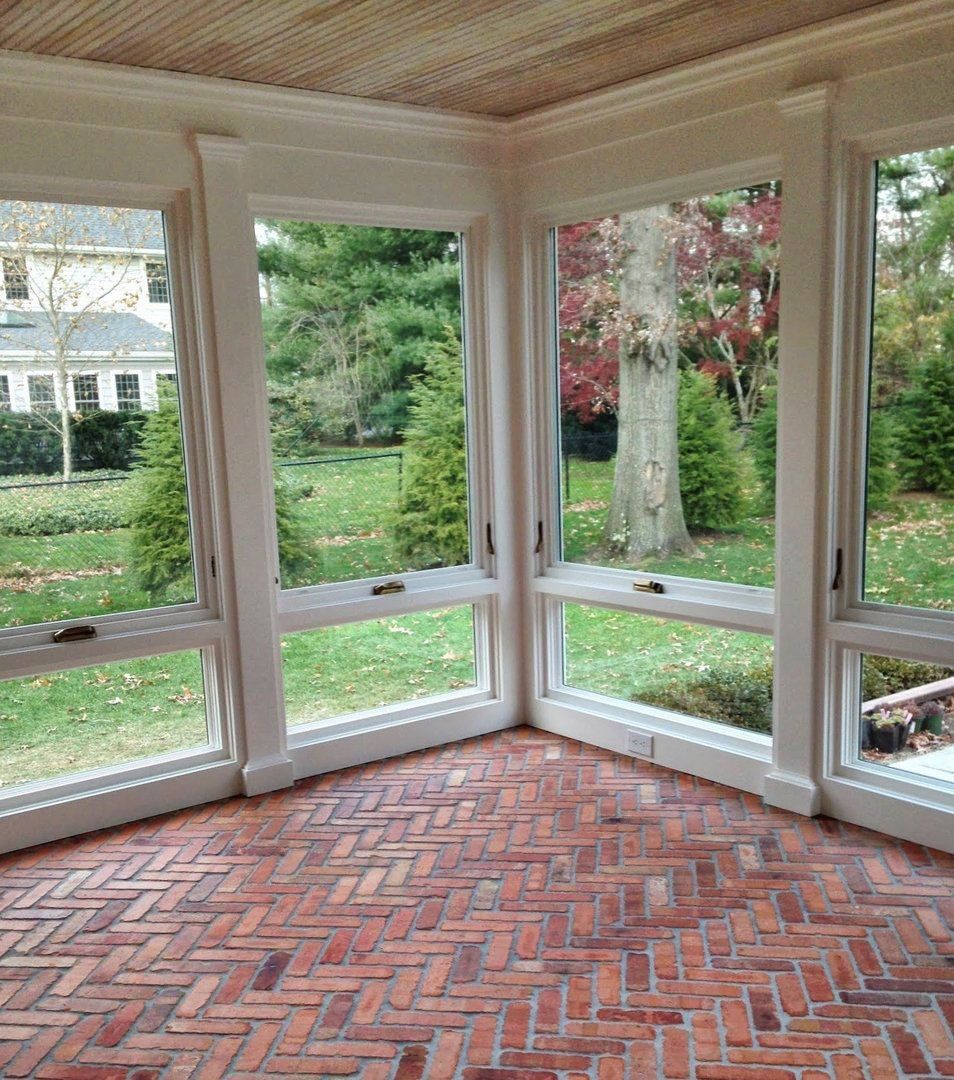 There are a lot of windows in this room with a brick floor.