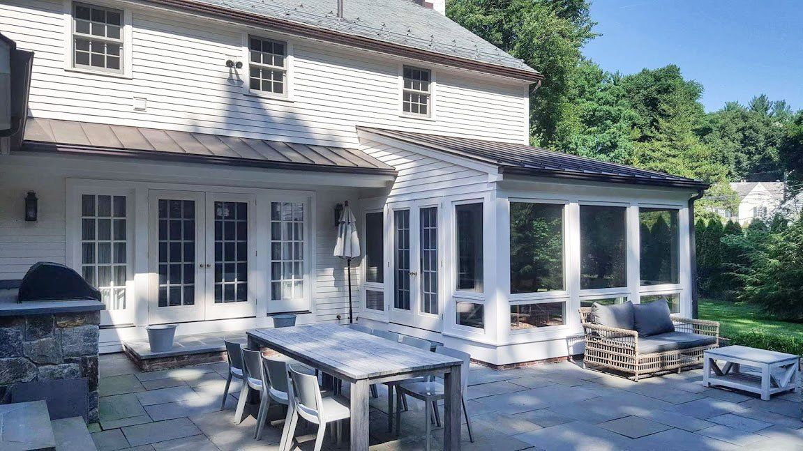 A large white house with a patio area with a table and chairs