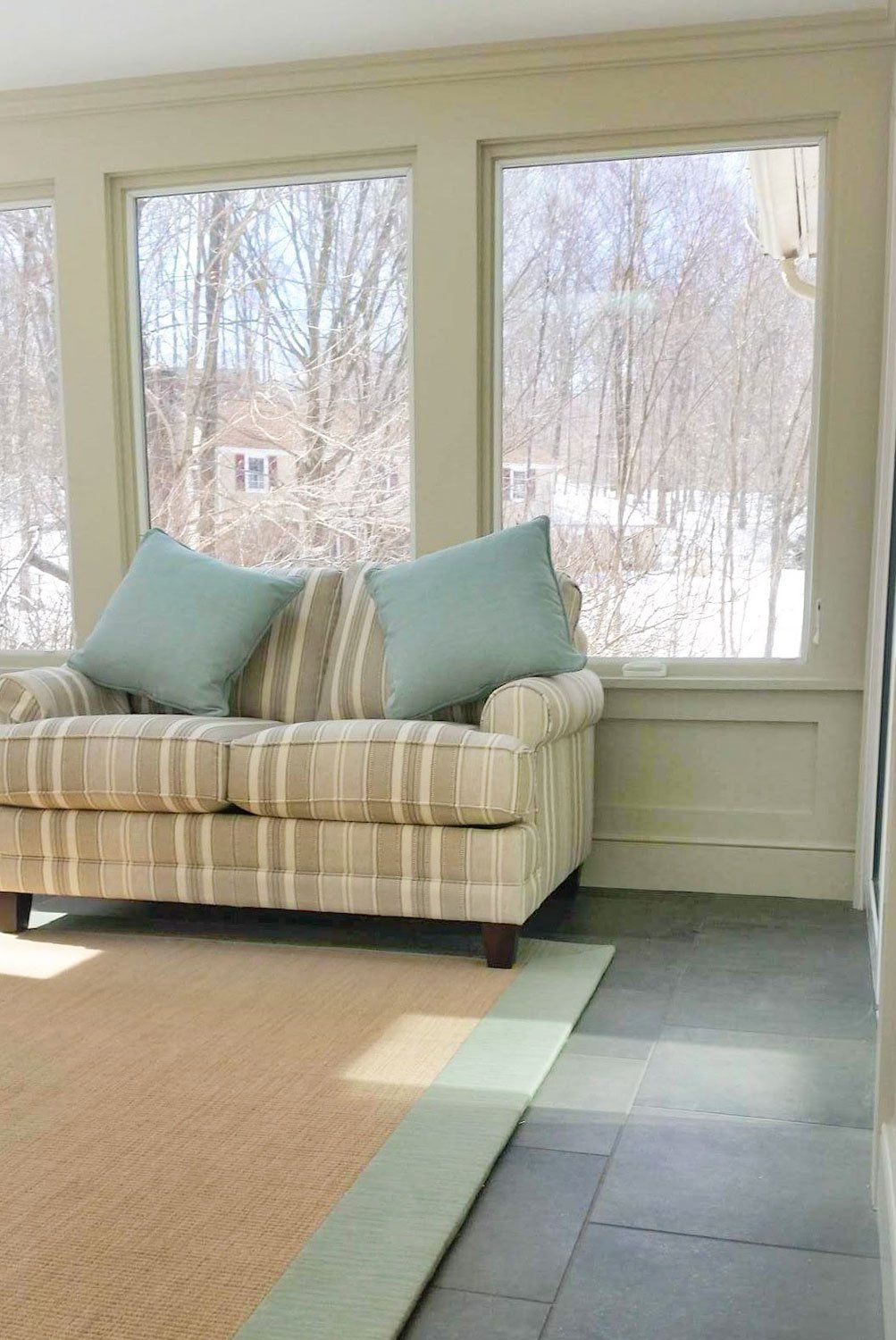 A living room with a couch and two windows.