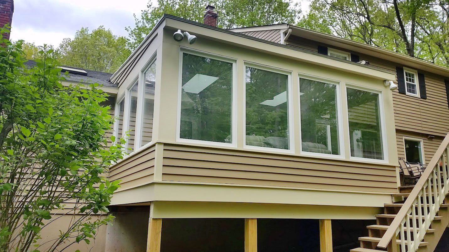 A house with a sunroom and stairs on the side of it.