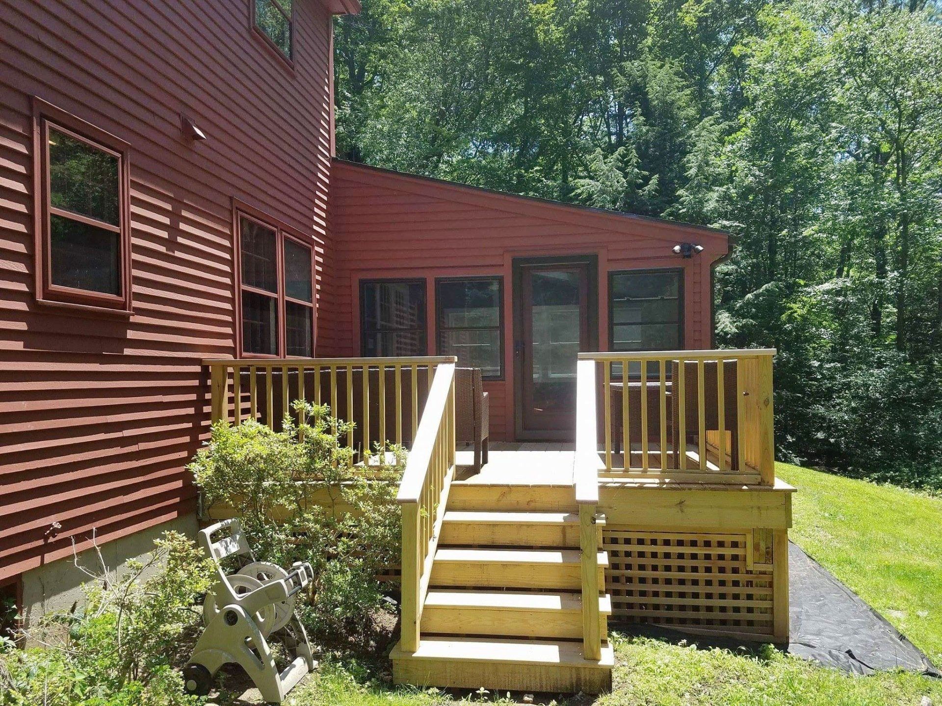 A red house with a wooden deck and stairs
