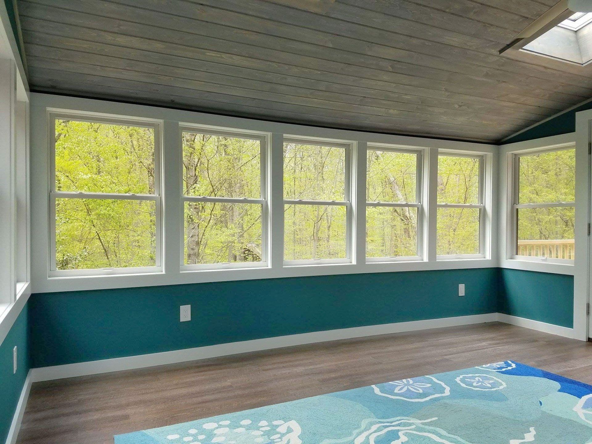A room with a lot of windows and a rug on the floor