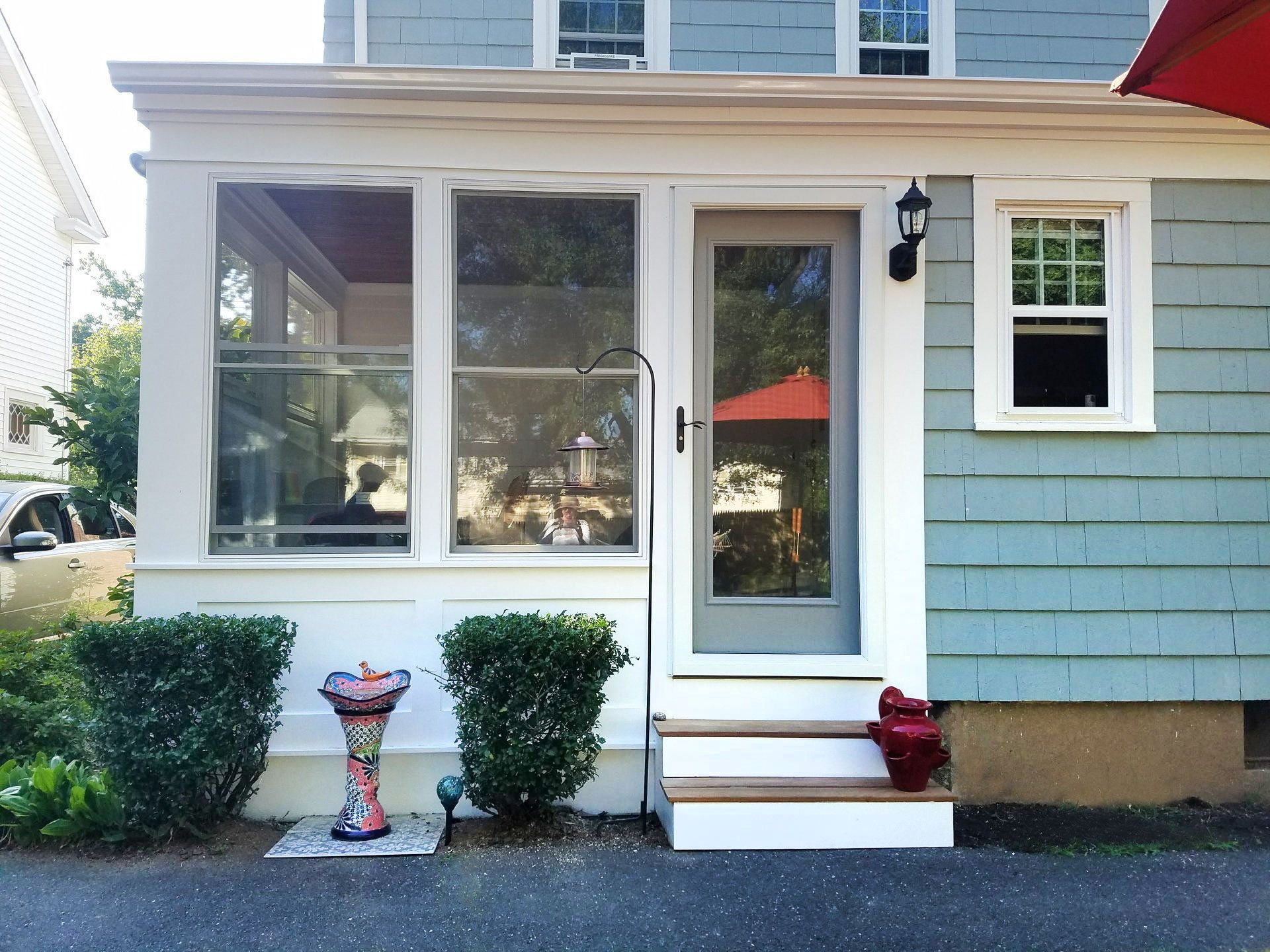 A house with a screened in porch and a red umbrella