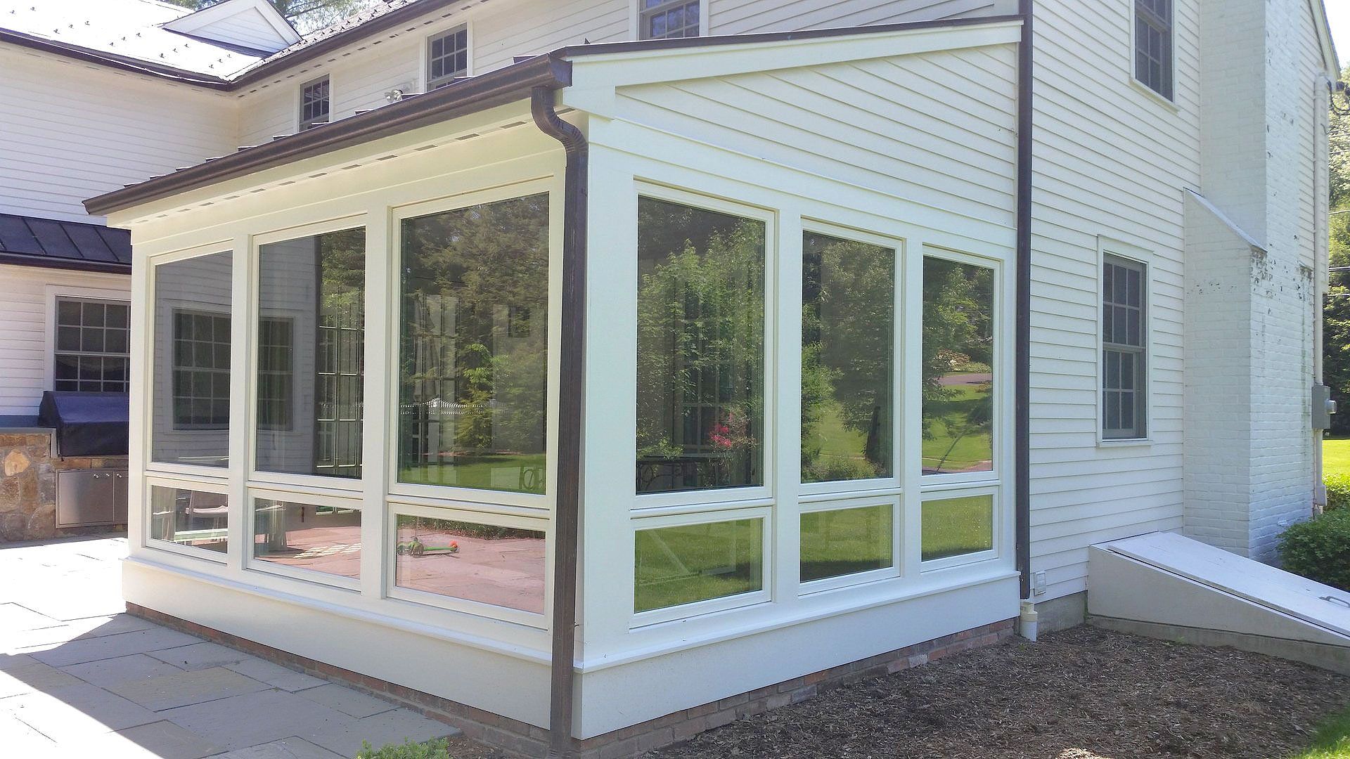 A white house with a screened in porch on the side