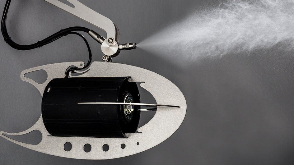 A suspended ceiling-mounted industrial misting system spraying a fine water fog in multiple directions.