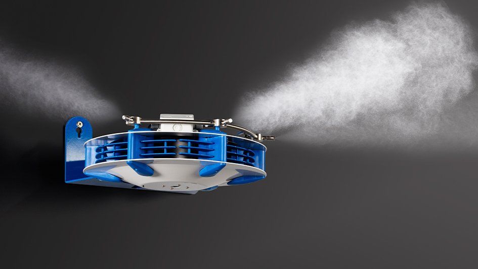 A suspended ceiling-mounted industrial misting system spraying a fine water fog in multiple directions.