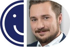 A headshot of a smiling man with a mustache framed inside a circular cutout, placed alongside the left half of a blue smiley face logo.