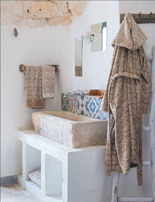 un bagno con arredi in bianco e biancheria beige