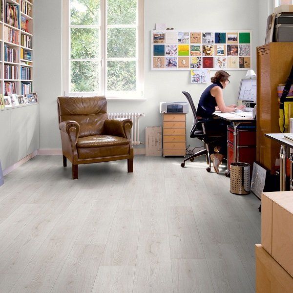 A woman sits at a desk in a room with a chair