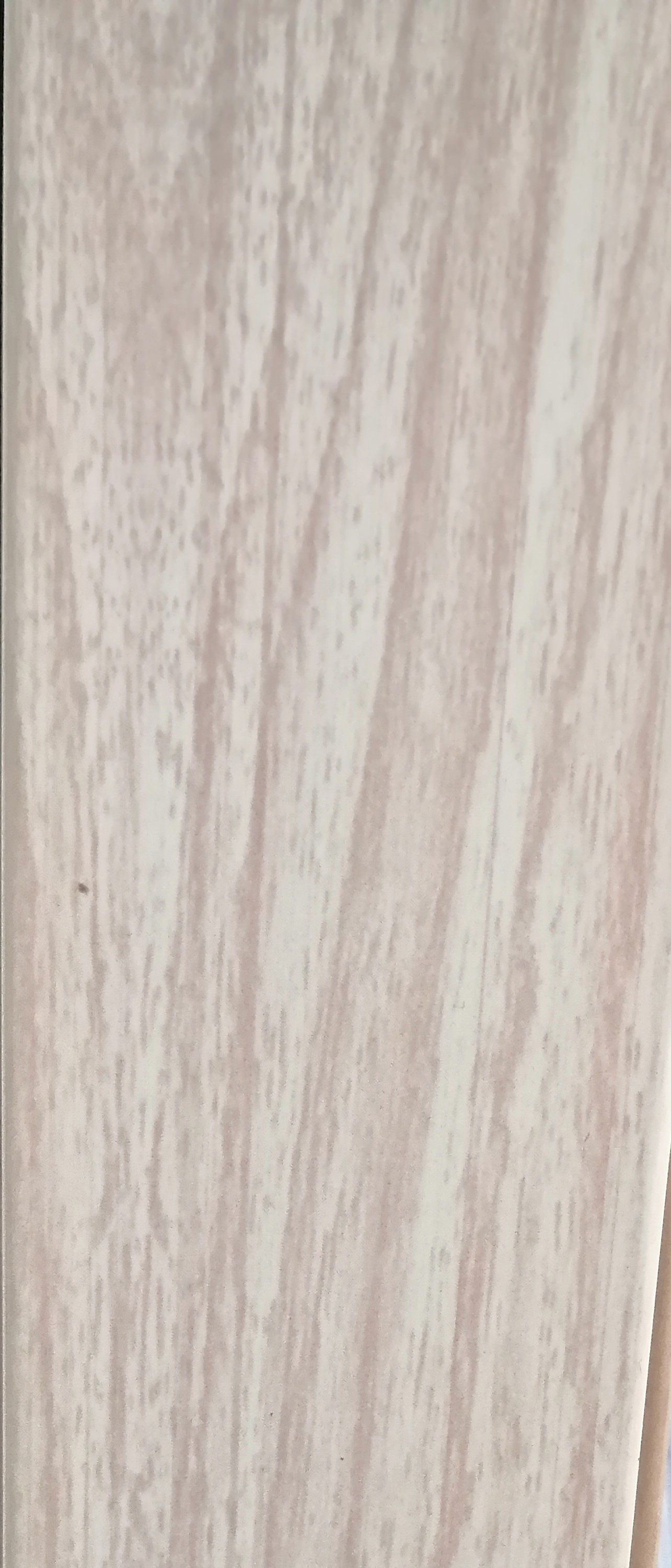 A close up of a white tile with a wood grain texture.