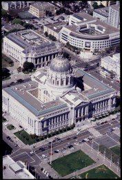 Aerial view of San Francisco City Hall with a large dome, surrounded by other buildings and streets.