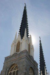 Two church steeples, gray stone and white details, against a bright, hazy sky.