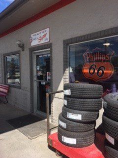 Tire shop exterior with stacked tires and Phillips 66 logo in the window.