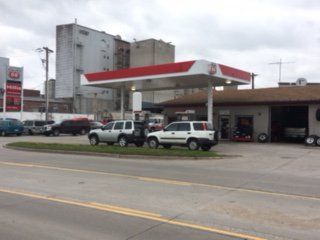 Gas station with red and white canopy; cars parked.