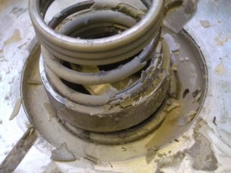Beschädigte Industriefeder mit abblätterndem, abgenutztem Material.