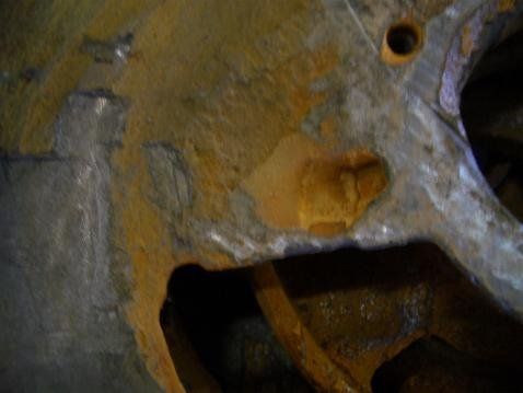 Nahaufnahme von stark verrostetem Metall mit unregelmäßigen Formen und einem kreisrunden Loch.
