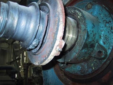 Beschädigte Industriemaschine: eine dunkle Metallschraube mit Lager, die Gebrauchsspuren und Bruchstellen aufweist.
