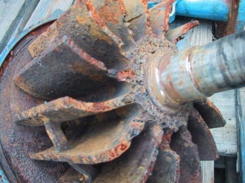 Rostiges Metalllaufrad, das an einer korrodierten Welle befestigt ist, Teil einer Pumpe oder einer ähnlichen Maschine.