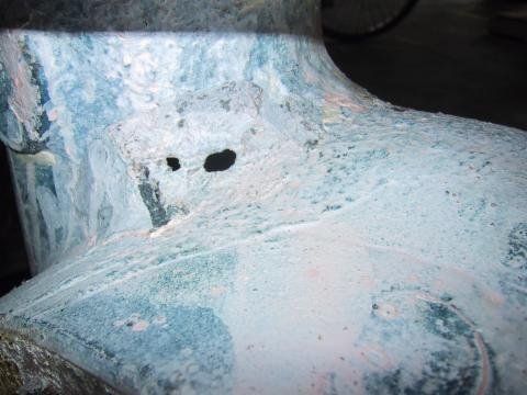 Nahaufnahme eines blau-weißen Objekts mit zwei Löchern, möglicherweise verwittert oder beschädigt.