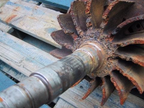 Rostiges Metalllaufrad auf einer Palette mit zentraler Welle.