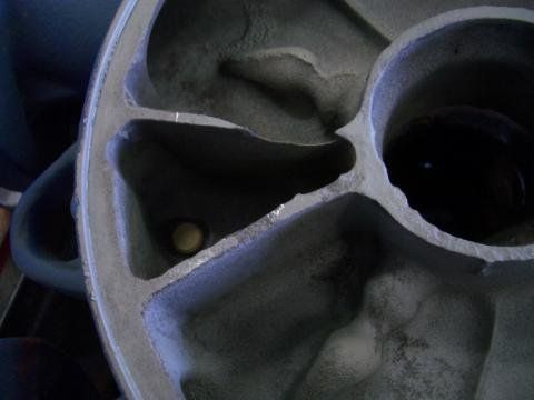 Nahaufnahme eines beschädigten, metallisch grauen Laufrads mit Hohlräumen und einer zentralen Nabe.