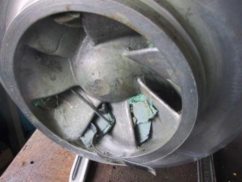 Beschädigtes Metalllaufrad, an dessen Schaufeln abgebrochenes grünes Material haftet.