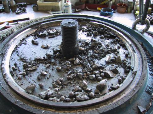 Nahaufnahme des Inneren einer Industriemaschine mit Trümmern und einer zentralen Schraube.