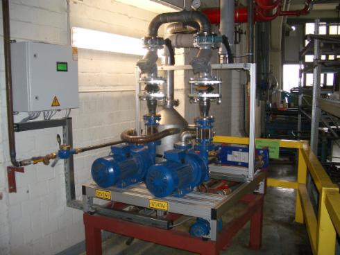 Zwei blaue Pumpen und Rohrleitungen in einer industriellen Umgebung, mit einem Schaltkasten an der Wand.
