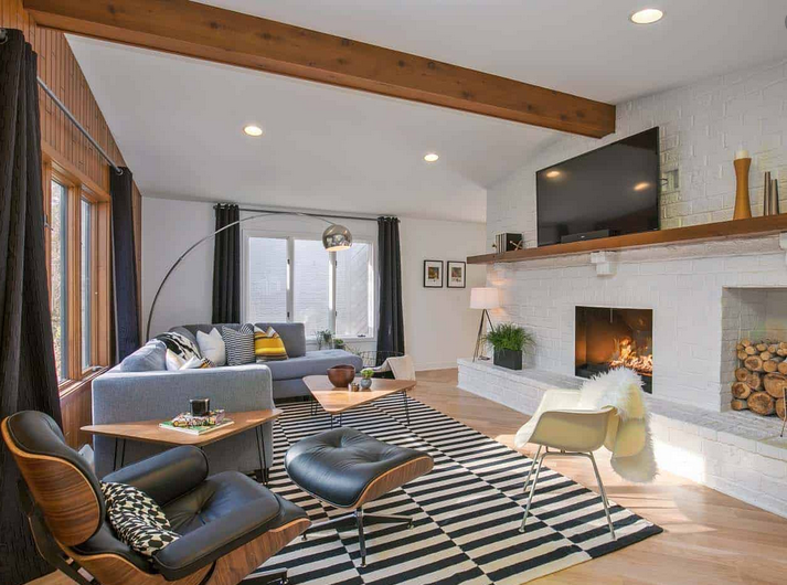 A living room with a couch , chair , rug , fireplace and television.