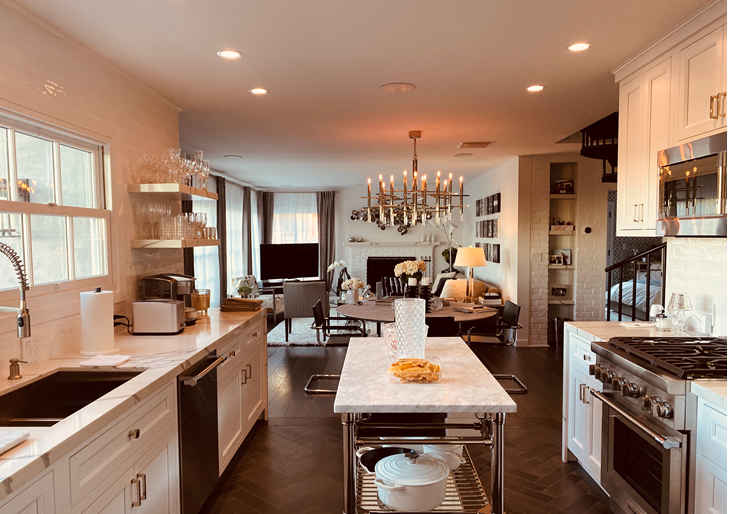 A kitchen with white cabinets , a stove , a sink , and a large island.