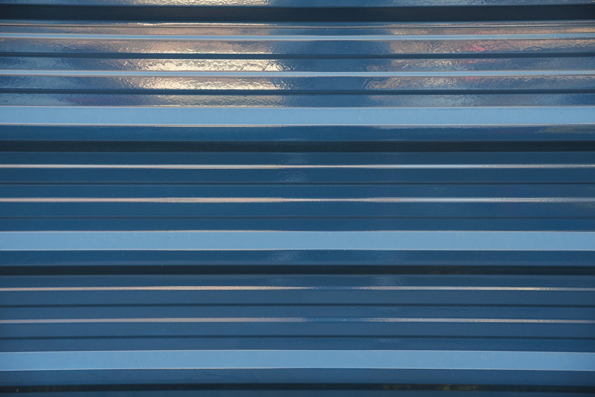 Blue corrugated metal surface with horizontal ridges and light reflections