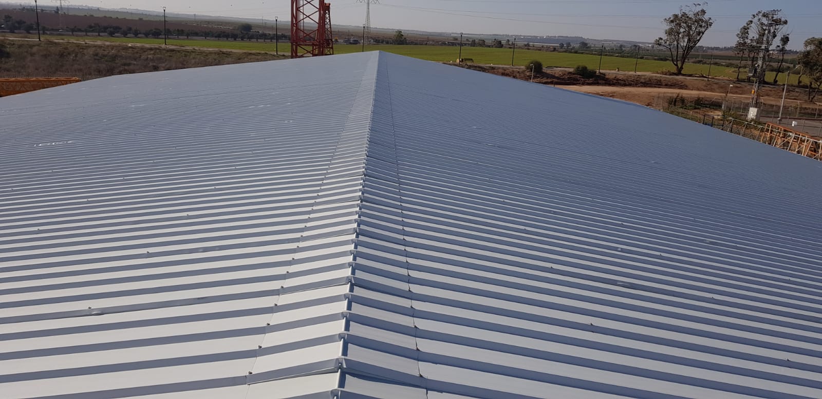 Corrugated metal roof panels leading to a distant rural landscape under a hazy sky