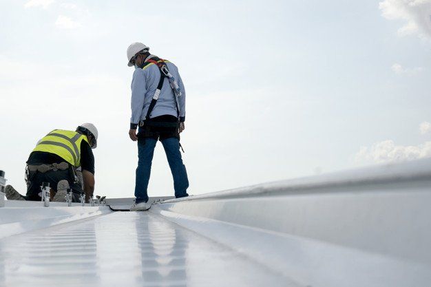 Two workers inspecting a reflective rooftop under a bright sky