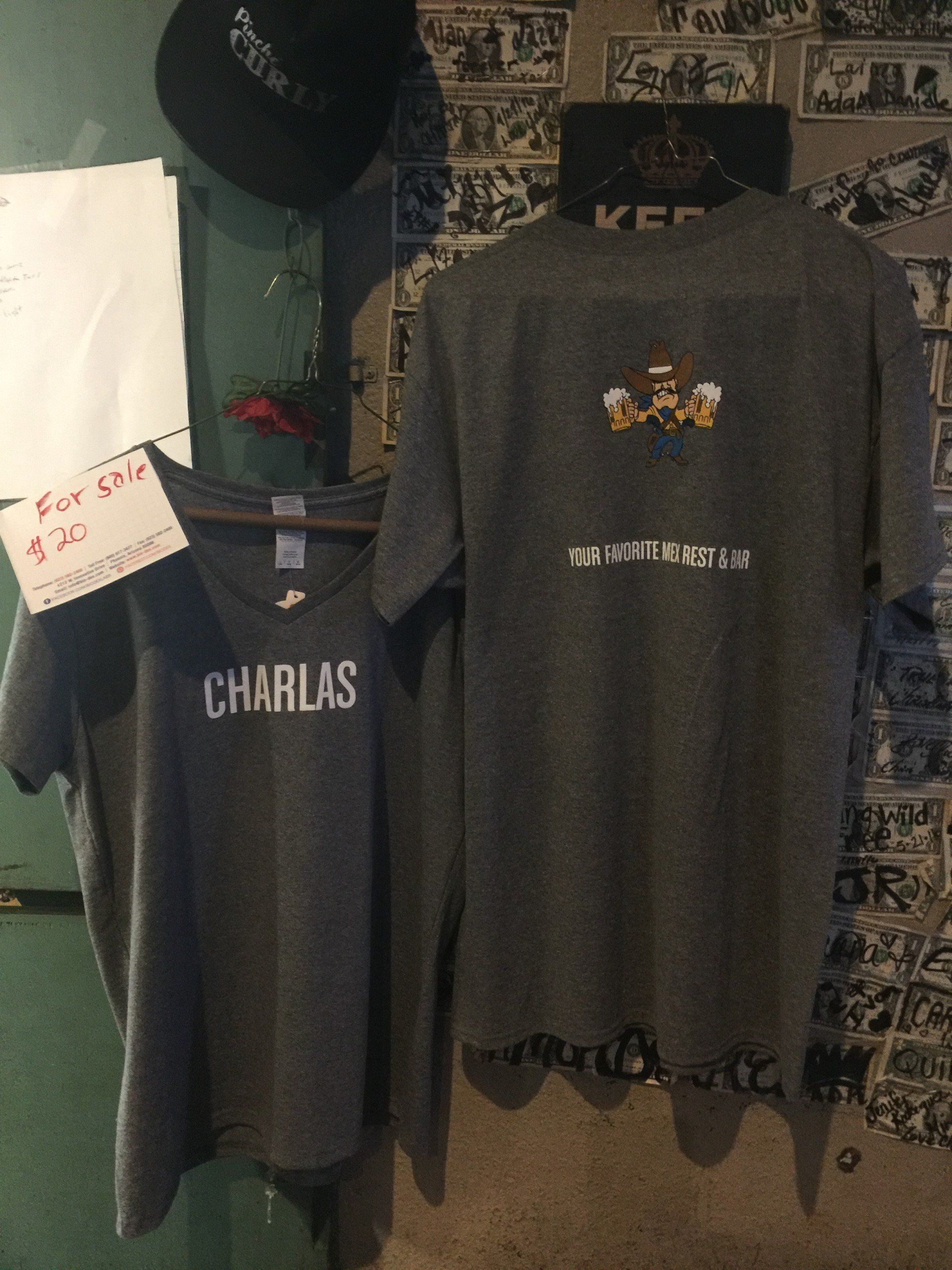 Two shirts hanging on a hanger with one that says charlas on it