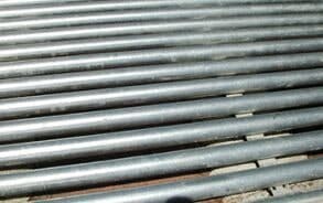 A row of metal pipes sitting on top of a brick floor.
