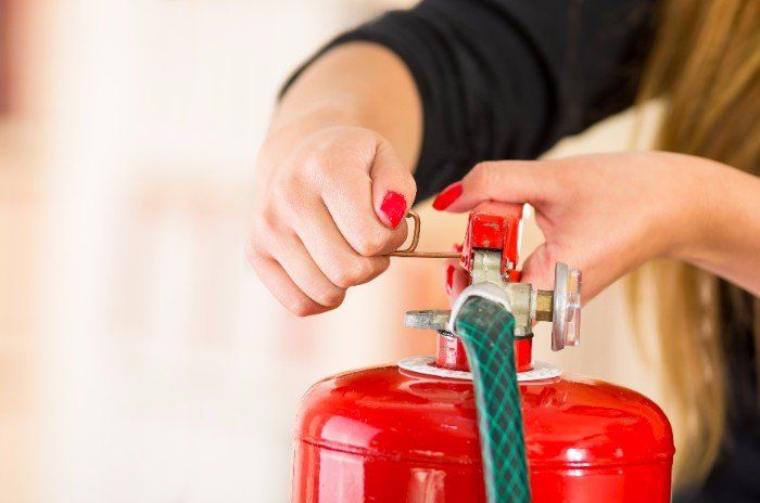 Donna togliendo il passatore di sicurezza di un estintore