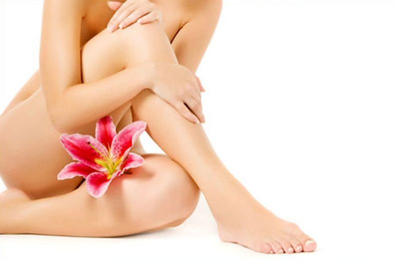 un'estetista mentre depila le gambe a una donna con una striscia di cera