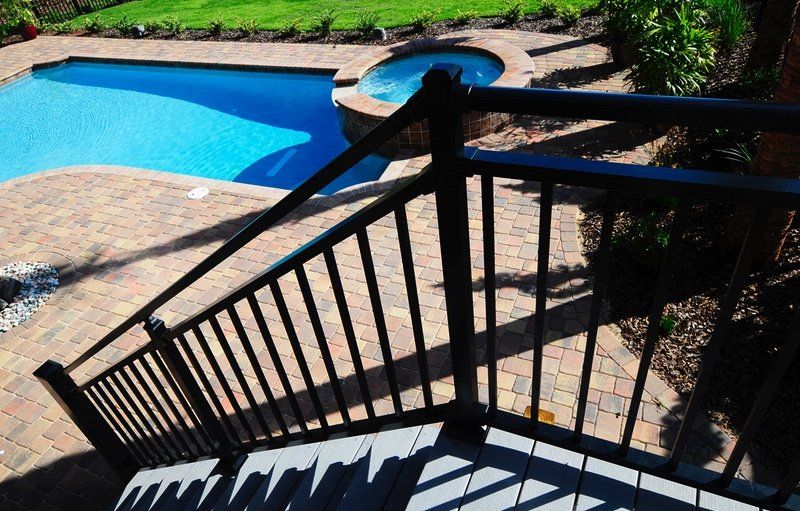 A staircase leading to a pool with a black railing