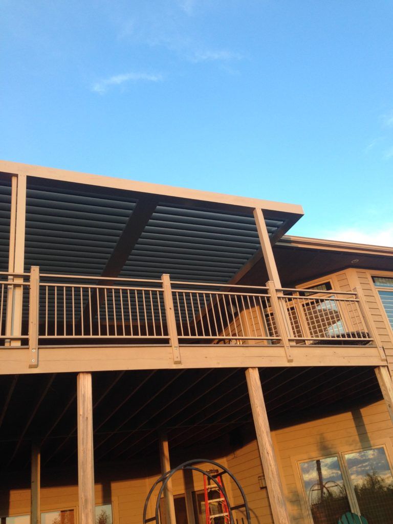 A house with a balcony and a motorized louvered pergola