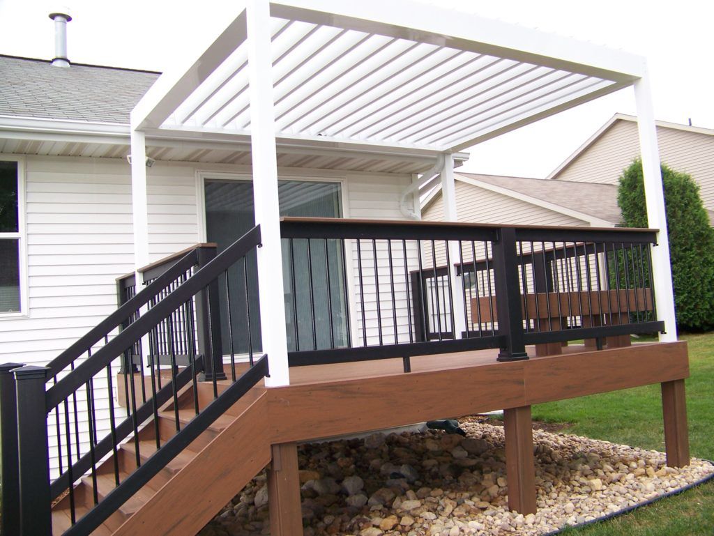 A deck with a white motorized pergola and stairs leading up to it