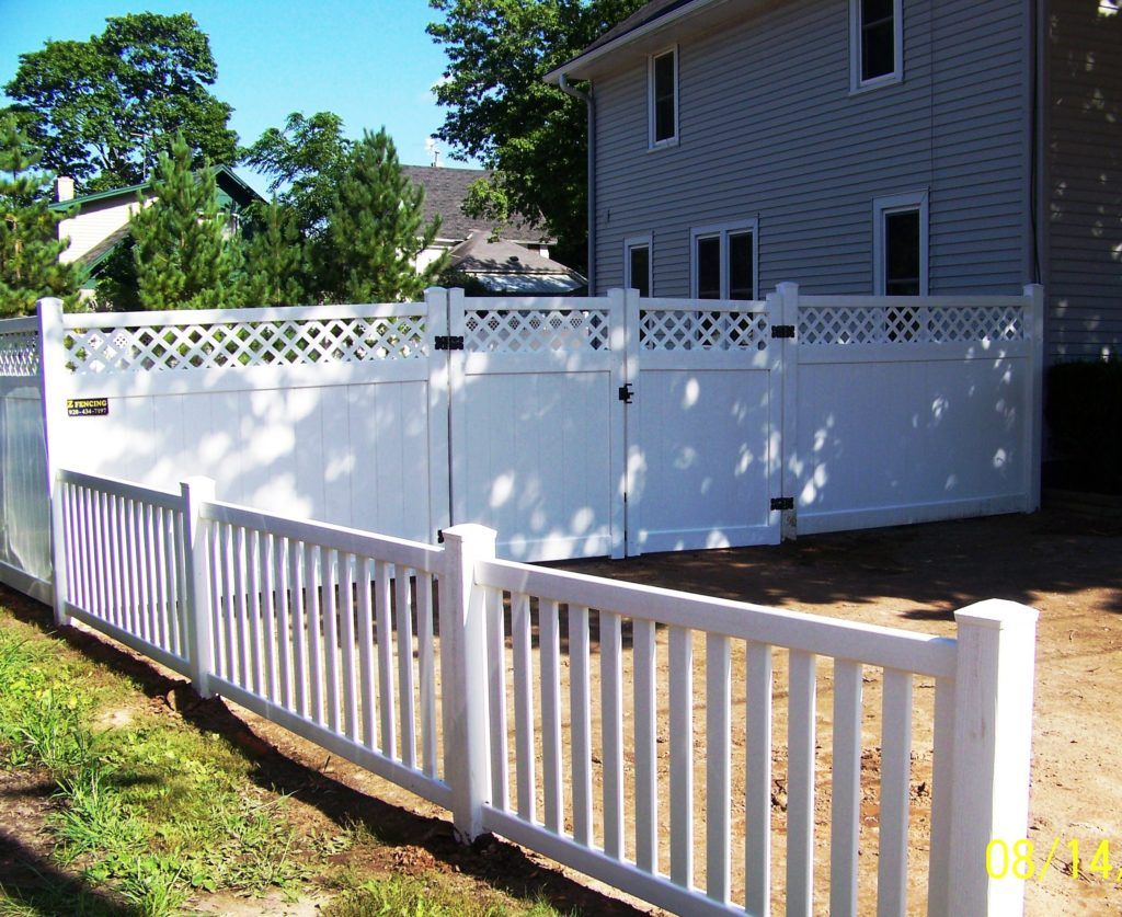 A white vinyl fence with a gate in front of a house