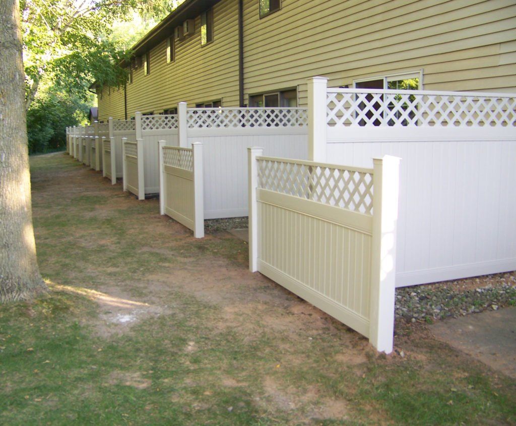 A row of white  vinyl fences in front of a building
