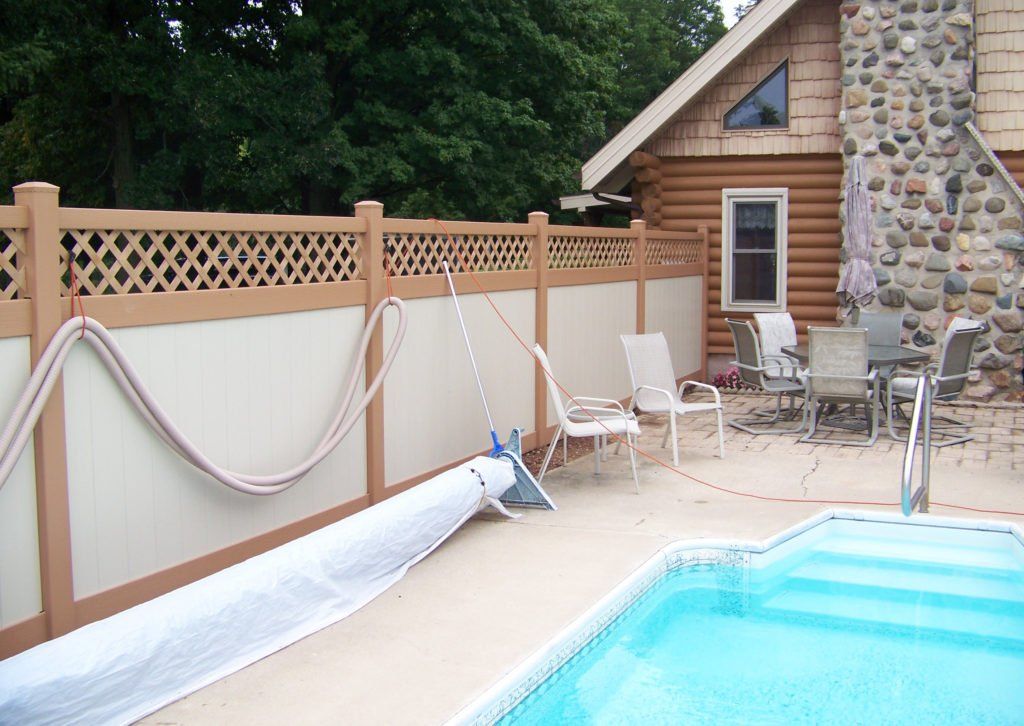 A vinyl fence surrounds a swimming pool with a lattice top