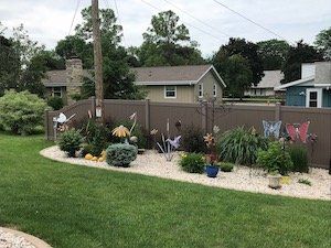 A backyard with a vinul fence and lots of plants and flowers.