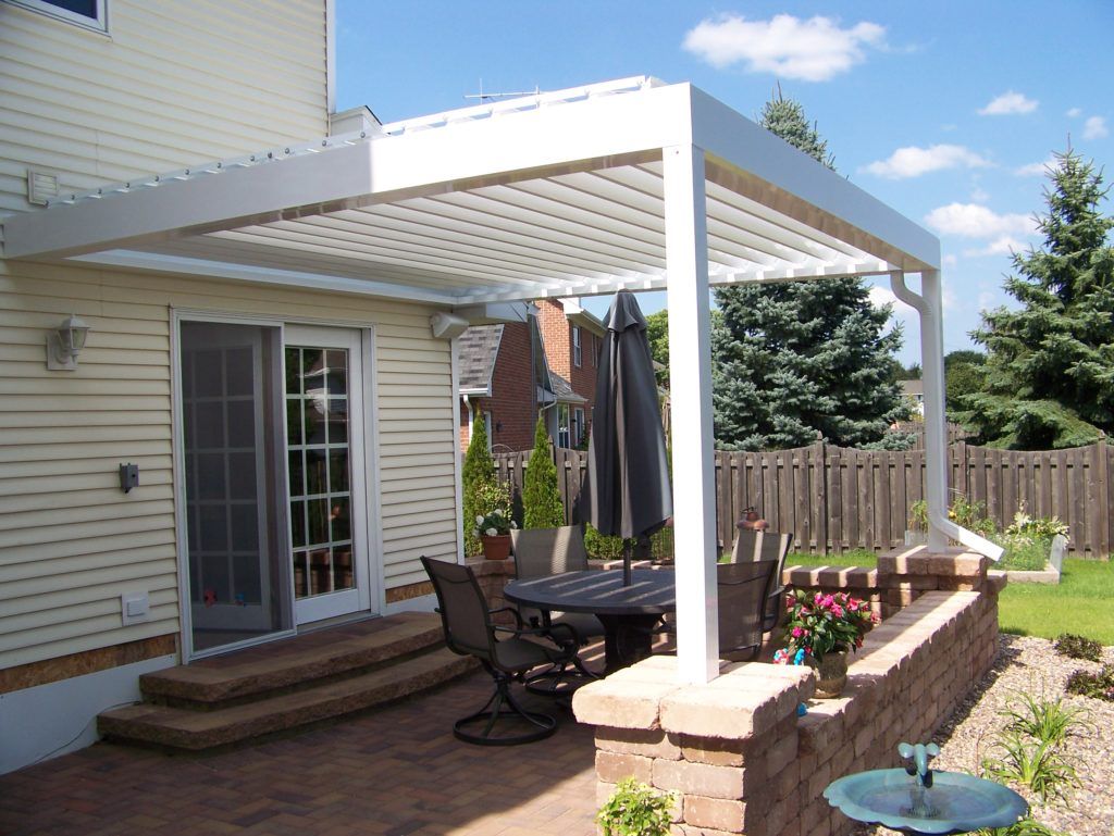 A patio with a table and chairs under a louvered motorized pergola
