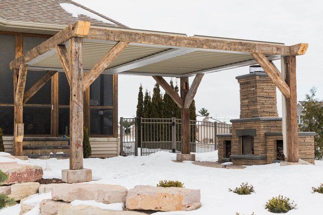 A wooden frame and motorized pergola is sitting in the snow